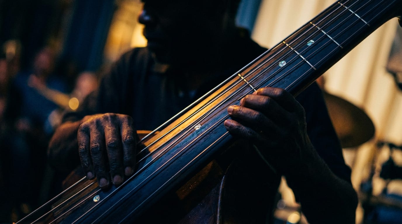 Upright bass fingerboard detail showing strings and fret markers, warm amber glow