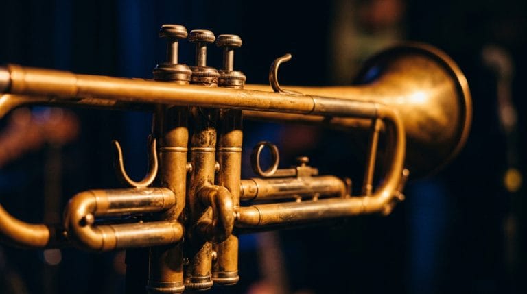 Close-up of vintage brass trumpet with three valves against dark blue background, jazz instrument