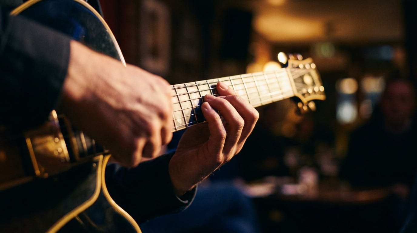 Musician's hands playing acoustic guitar fretboard in warm stage lighting during jazz performance