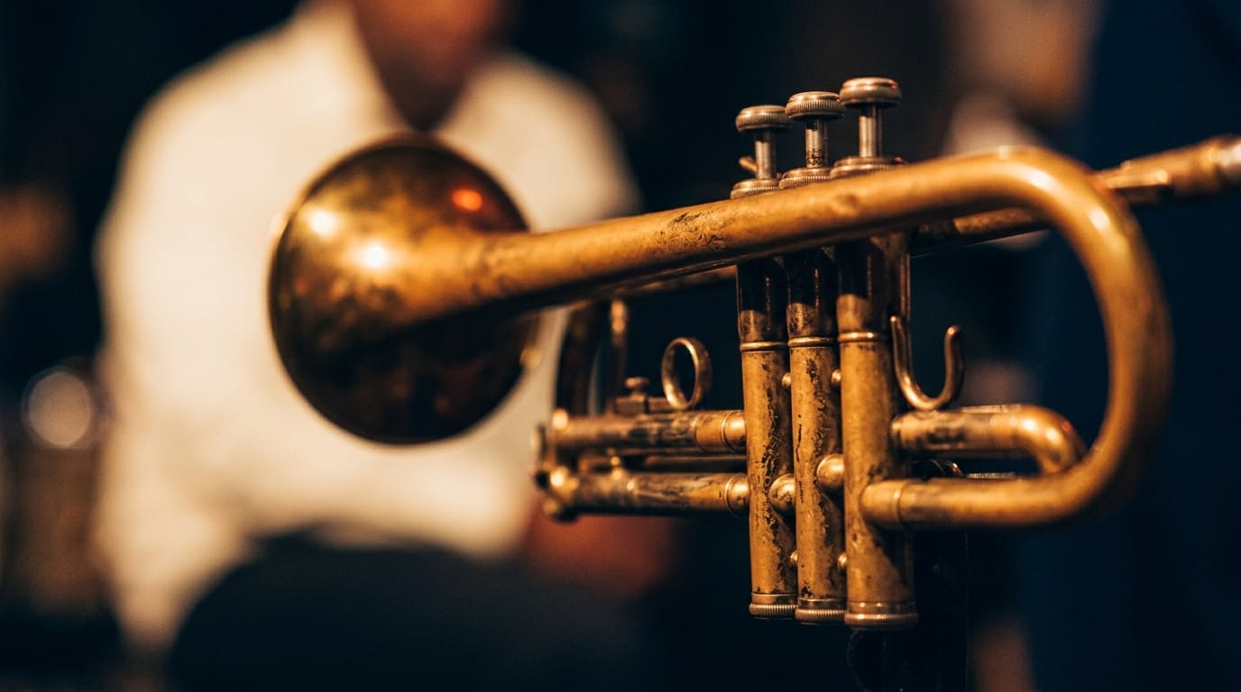 Close-up of vintage brass trumpet with musician in white shirt blurred background