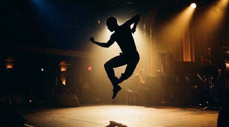 Silhouetted jazz dancer leaping on stage with dramatic golden spotlight lighting