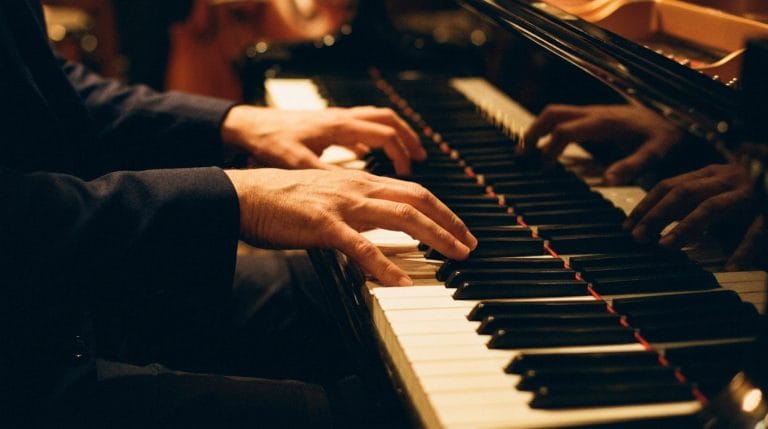 Jazz pianist's hands performing on grand piano keys with warm stage lighting