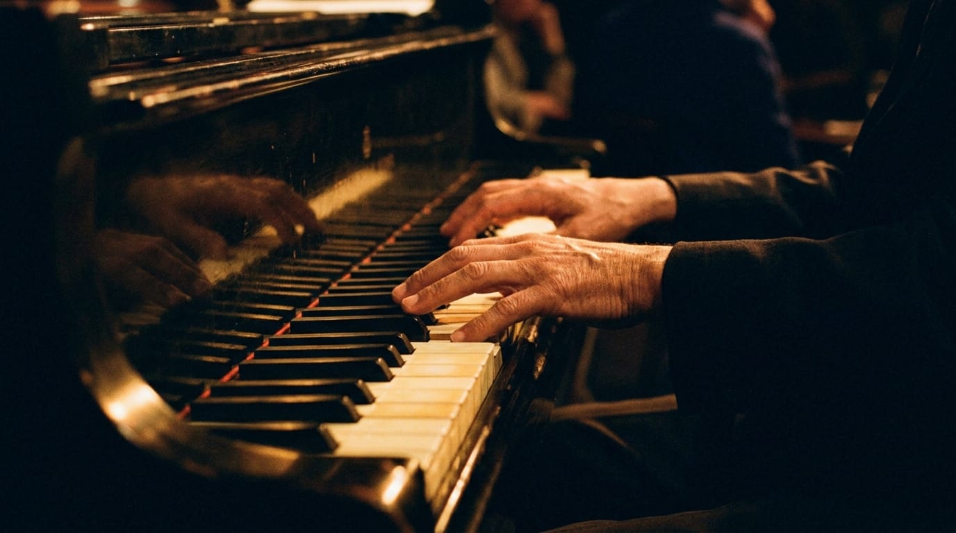 Experienced pianist hands playing grand piano keys in warm stage lighting during jazz performance